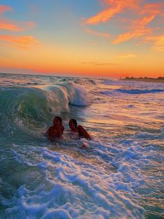 two people swimming in the ocean at sunset with waves coming up to their heads and one person laying on his stomach