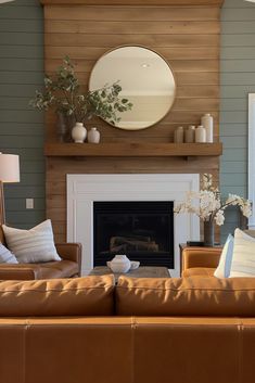 a living room filled with furniture and a fire place in front of a mirror on the wall