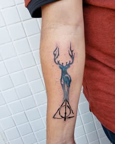 a man with a tattoo on his arm has a harry potter triangle and deer head