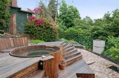 a hot tub sitting on top of a wooden deck next to a lush green forest