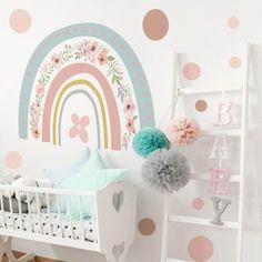 a baby's room decorated in pastel colors with polka dots and a rainbow wall decal