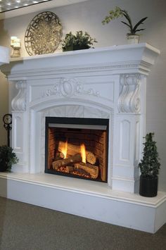 a white fireplace with logs and plants on top