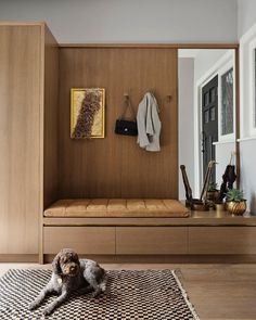 a dog laying on the floor in front of a wooden bench with coat rack above it