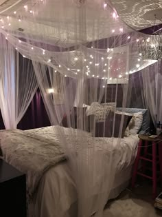 a bed with white netting and lights hanging from it's headboard in a bedroom