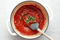 a pot filled with red sauce and garnished with parsley on the side