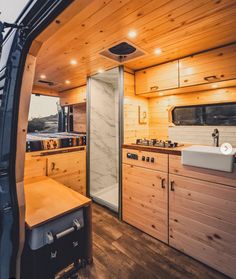 the inside of a camper with wood paneling and white sink, cabinets, and counter tops