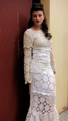 a woman standing next to a wall wearing a white dress and holding her hands on her hips