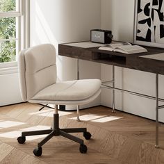 a white office chair sitting in front of a desk with an open book on it