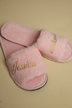 a pair of pink slippers with personalized name on them sitting on a table