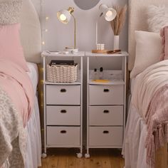 two small white drawers in a bedroom next to a bed with pink sheets and pillows