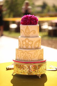 a three tiered wedding cake with pink flowers on top is sitting on a table