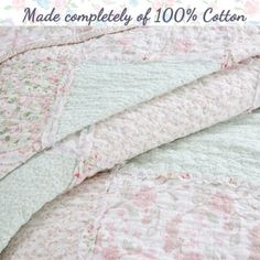 an unmade bed with pink, green and white quilted bedspread on it