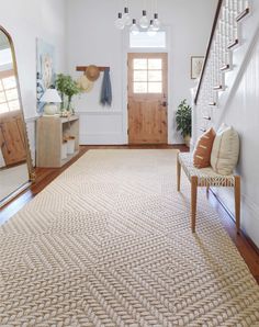 a large area rug is on the floor in front of a staircase and entryway