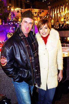 a man and woman standing next to each other in front of a building at night