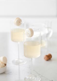 two wine glasses filled with champagne and marshmallows on a marble countertop