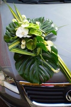 a bouquet of flowers is placed on the hood of a car with greenery in it