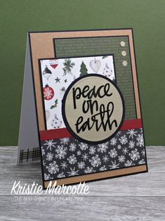 a card with the words peace on it and snowflakes around it, sitting on top of a wooden table