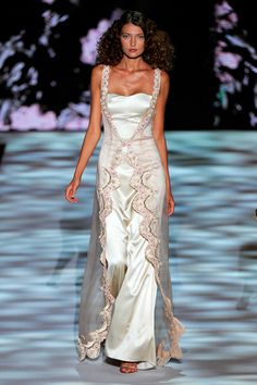 a woman walking down a runway in a white dress