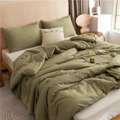 an unmade bed with green sheets and pillows