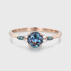 a rose gold ring with an oval blue topazte surrounded by three small diamonds