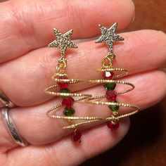 someone is holding two christmas tree earrings in their hand