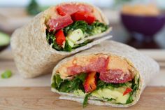 two wraps filled with vegetables and meat on top of a cutting board