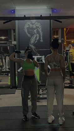 two women standing in front of a gym machine