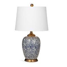 a blue and white table lamp with a white shade on the top, sitting against a white background