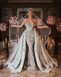 a woman standing in front of a fireplace wearing a wedding dress and veil with flowers on it