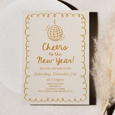 a white and gold new year's eve party card with a feather on it