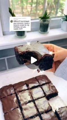 someone is holding up a piece of chocolate brownie with white frosting on it