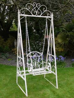 a white metal swing chair sitting in the grass