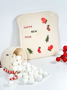 a bowl with marshmallows in it next to a plate that says happy new year