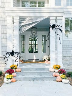 a white house decorated for halloween with pumpkins and spider decorations