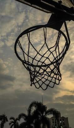 a basketball hoop with the sun setting in the background and palm trees on the other side