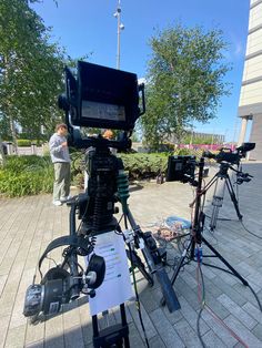 a camera set up on a tripod in front of a building with people looking at it