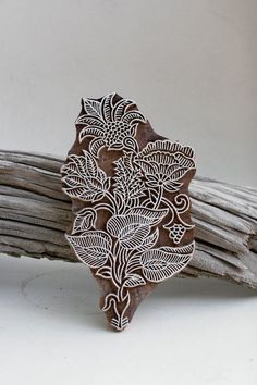 an intricately designed wooden brooch sits on top of some branches