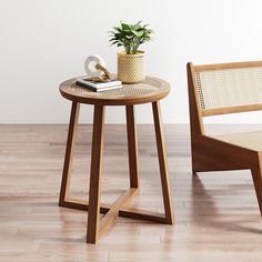 a small table with a potted plant on it next to a chair in a room