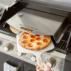 a pizza being cooked on the grill with a spatula in it's hand