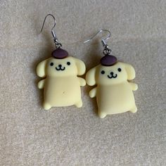 two yellow dog shaped earrings on top of a carpeted floor next to each other