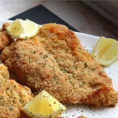 fried chicken with lemon wedges on a white plate