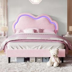 a pink bed with a teddy bear sitting on the foot board in front of it