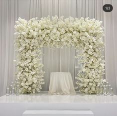 a white wedding arch decorated with flowers and candles