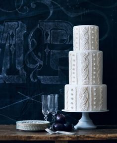 a three tiered cake sitting on top of a table next to plates and glasses