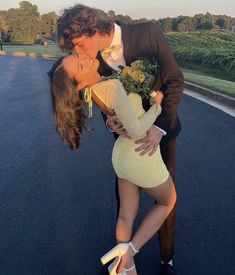 a man kissing a woman on the cheek in front of an open road with trees