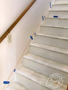 some blue tape is taped to the bottom of a stair case on a white wall