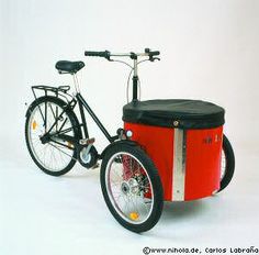 a red bike with a black seat and basket on the front is parked against a white background