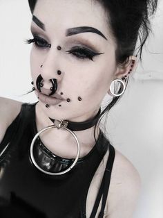 a woman with black makeup and piercings on her face