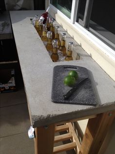 an apple sitting on top of a cutting board next to bottles of liquid and a knife