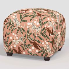 a pink and green patterned ottoman with wooden legs